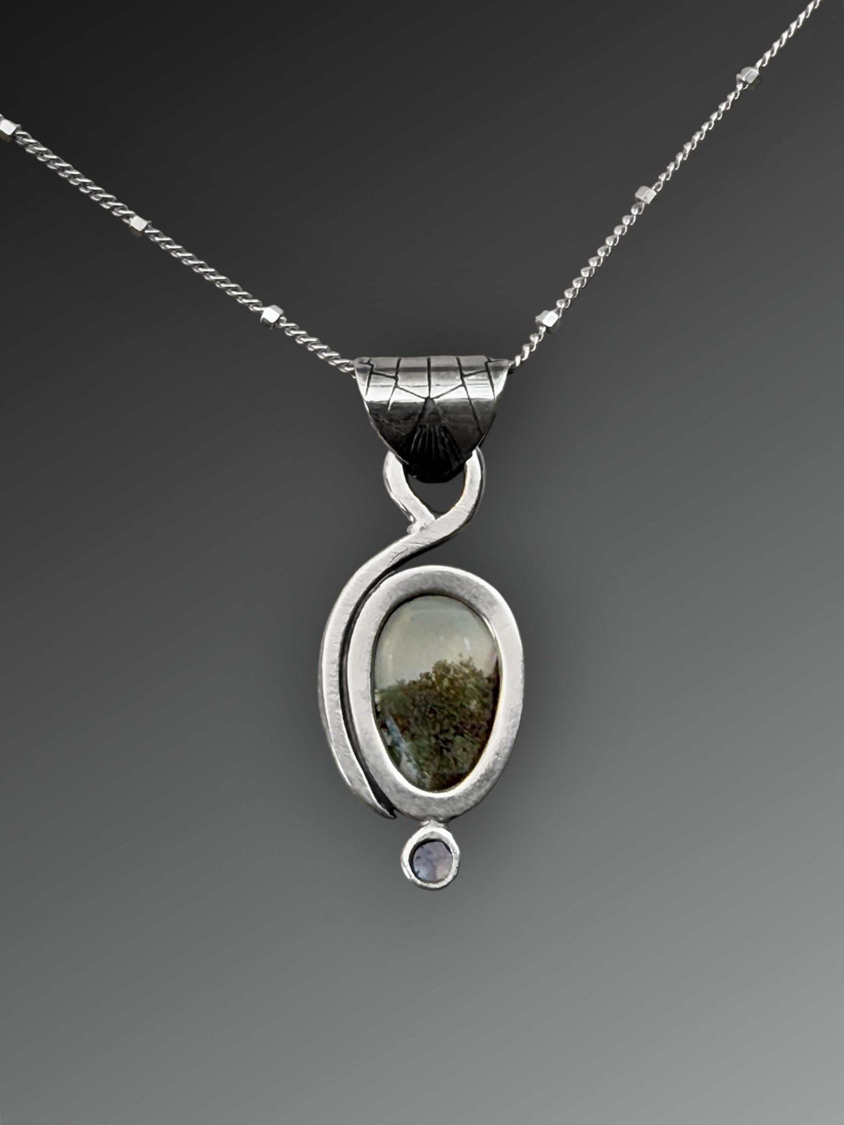 Reverse side of a silver pendant with two stones on a gray background